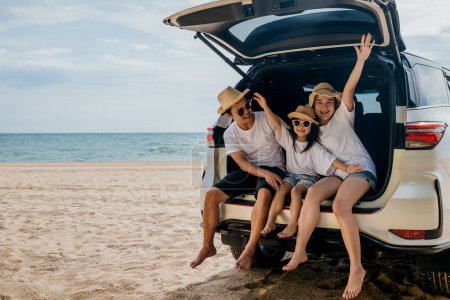 Photo for Family Day. Father, Mother and daughter enjoying road trip sitting on family back car raise hand up, Happy people having fun in summer vacation on beach, Family traveling in holiday at sea beach - Royalty Free Image