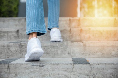 Photo for With sneakers on, a woman takes on the city stairway, showcasing her determination and progress. Each step is a reflection of her unwavering journey towards success and personal growth. step up - Royalty Free Image