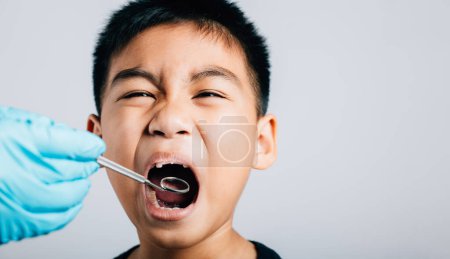 Photo for In a pediatric dentists clinic a doctor examines a childs mouth post removal of loose milk tooth. Dental tools help in detailed examination process. Doctor uses mouth mirror to checking teeth cavity - Royalty Free Image