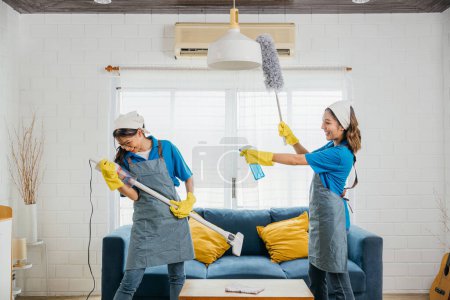 Photo for Asian maid playful twist, vacuum guitar fun while cleaning. Husband humor sparks joyful singing dancing. Music-infused service brings excitement to housework. Cleaning is fun - Royalty Free Image