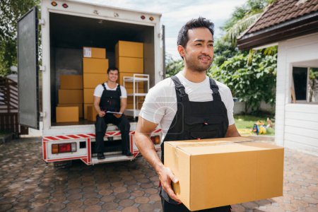 Photo for Young delivery men unload boxes outdoors. Movers cooperate in relocation service. Teamwork among colleagues. Smiling workers carrying boxes. relocation cooperation Moving Day - Royalty Free Image