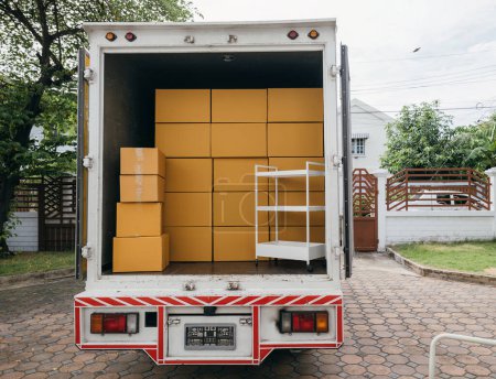 Photo for Logistic service outdoors, Open car trunk carrying moving cardboard boxes. White delivery van for house relocation. Transporting items scene. Moving Day Concept. - Royalty Free Image