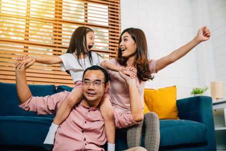 Foto de Una familia asiática feliz padre madre e hija comparten momentos afectuosos en un cómodo sofá en su casa moderna abrazando la unión durante el auto-aislamiento. - Imagen libre de derechos