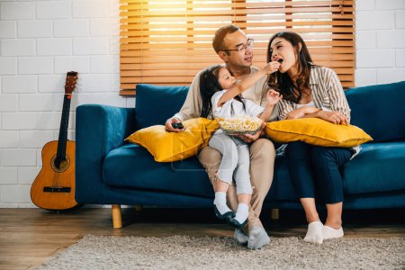 Photo for Family finds relaxation and joy while watching TV with popcorn at home. father mother son daughter and schoolgirl share moments of happiness creating cherished memories during their quality time. - Royalty Free Image
