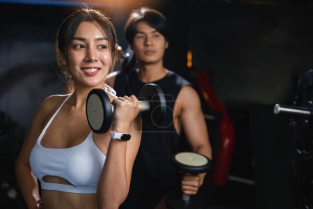 Photo for A fit couple in black workout clothes, smiling cheerfully while holding dumbbells, works together to build their muscular bodies and achieve their fitness goals. lifestyle fitness concept - Royalty Free Image