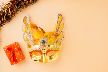 Foto de Happy Purim carnival decoration. Golden venetian ball mask, carnival mask isolated on pastel background, Purim or Mardi Gras in Hebrew, Masquerade party event - Imagen libre de derechos