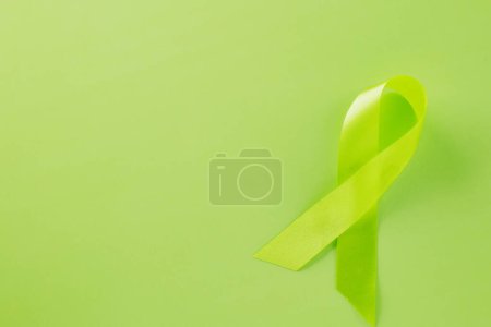 Téléchargez les photos : Green awareness ribbon symbol of Gallbladder and Bile Duct Cancer month isolated on green background with copy space, concept of medical and health care support, Cancer awareness, World bipolar day - en image libre de droit