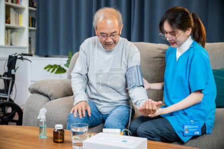Photo for Asian doctor woman examine do checking old man client heart rate with pulsimeter monitor, nurse visit patient senior man at home she measuring arterial blood pressure on arm in living room, Healthcare - Royalty Free Image