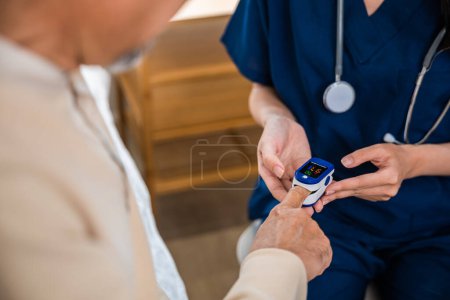 Foto de Mujer joven poniendo oxímetro digital de dedo adulto de mediana edad paciente para la medición, enfermera comprobando con dedo pulso oxímetro oxímetro medidor de oxígeno monitor de sangre dedo de anciano mayor en el hospital - Imagen libre de derechos