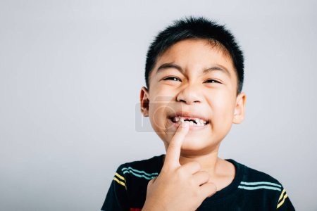 Téléchargez les photos : Un écolier de six ans indique volontiers un écart molaire croissant. joyeux voyage enfant portrait mignon en perdant dents de bébé primaires mettant en valeur la joie et les soins dentaires. dents nouvelles lacunes problèmes de dentiste - en image libre de droit