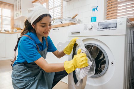 Photo for Housewife hand in protective glove cleans and wipes washing machine. Highlighting regular housework and hygiene routine. Cleaner working glove house purity. Clean laundry. Maid Cleaning service. - Royalty Free Image