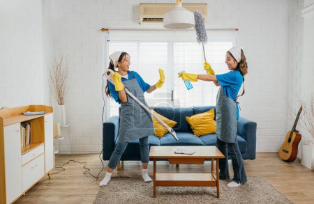 Photo for Maid upbeat routine, Asian woman plays vacuum guitar husband playful idea. Singing dancing joyfully. Music-infused service makes housework exciting. Cleaning is fun - Royalty Free Image