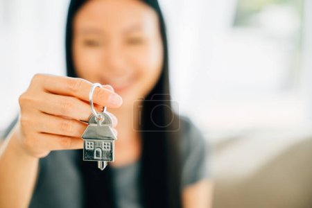 Foto de Una mano femenina sostiene una llave de la casa mostrando confianza y éxito en bienes raíces. Reflejando el logro de la felicidad y la emoción de comprar una nueva casa. - Imagen libre de derechos