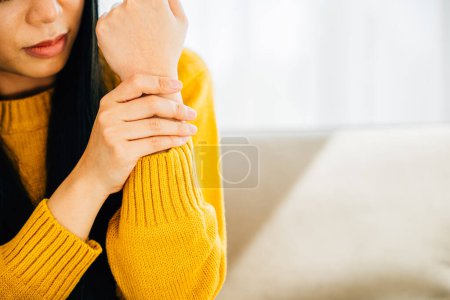Photo for Illustrating hand pain, Woman holds her achy wrist indicating Carpal Tunnel Syndrome or discomfort. Emphasizing inflammation symptoms and discomfort in the hands anatomy. Health care concept - Royalty Free Image