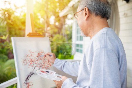 Photo for Lifestyle elderly people smile paint at his easel outside home, Asian senior old man painting picture using brush and oil color on canvas, Happy retirement artist and activity concept - Royalty Free Image