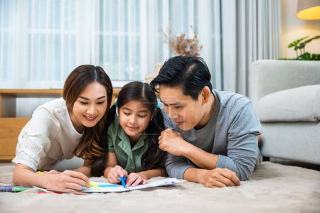 Photo for Smiling Father, Mother and daughter drawing together on paper at home, Asian family lying on floor painting with child daughter in living room, Happy family activity enjoy, learning draw art picture - Royalty Free Image