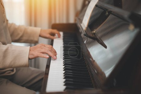 Téléchargez les photos : Happy relaxation Asiatique retraité homme avec des lunettes apprendre à jouer du piano à la maison, vieil homme âgé jouer de la musique au piano dans le salon, mode de vie après la retraite, Fermer les mains - en image libre de droit