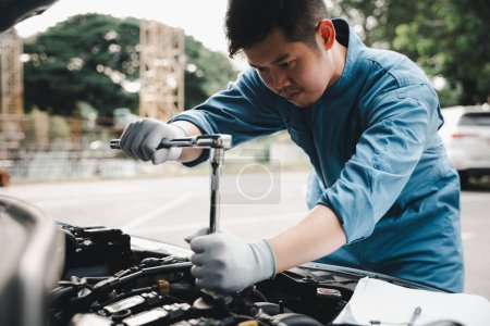 Téléchargez les photos : Service outdoor. Asian auto mechanic man working on car engine using wrench to repair and maintenance, broken car care check and fixed the problem and services insurance - en image libre de droit
