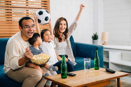 Téléchargez les photos : Avec enthousiasme, une famille et leur fille aiment regarder le football à la télévision à la maison, créant une atmosphère de convivialité et de liens. Leurs acclamations et leurs rires reflètent la joie du jeu. - en image libre de droit