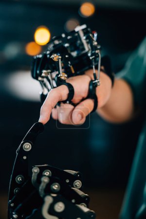 Foto de En una universidad técnica, un adolescente prueba una mano robótica y un brazo tocando los dedos para el desarrollo educativo. Abrazar la humanidad de IA y el aprendizaje innovador. - Imagen libre de derechos