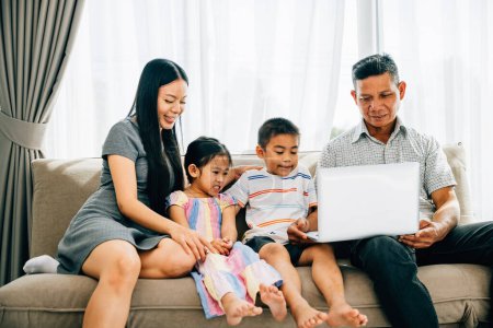 Photo for Parents and kids gathered on a sofa engrossed in a laptop smiling and exploring. The image showcases familial bonding joy and the magic of shared technology experiences. - Royalty Free Image