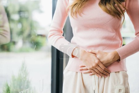 Foto de Sad Woman Stomach Ache from menstruation. young female unhappy unwell sick ill hand holding on stomach suffers pain at home, Abdomen bloating and Chronic gastritis concept - Imagen libre de derechos