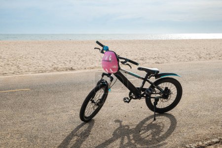 Téléchargez les photos : Une journée d'été tranquille se déroule avec un vélo pour enfants sur une plage de sable capturant l'esprit insouciant du tourisme où détente et sport se rencontrent sur fond de mer et de ciel dégagé. - en image libre de droit
