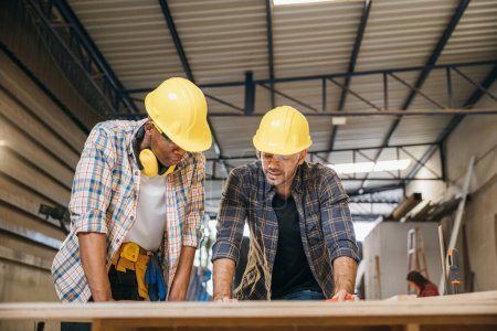 Zwei Schreinermeister treffen sich in Zimmerei-Werkstatt, Handwerker sprechen über Bauplan-Entwurf, Happy Carpenters Day
