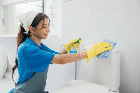 Photo for A woman in yellow rubber gloves meticulously wipes the restroom toilet seat with a cloth emphasizing importance of cleanliness and hygiene. Maid dedication is evident. Housekeeper healthcare concept - Royalty Free Image