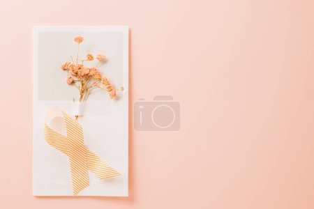Foto de Pink awareness ribbon sign and paper card flower of World Cancer Day on pink background with copy space, concept of medical and health care support, Breast cancer awareness concept, 4 February - Imagen libre de derechos