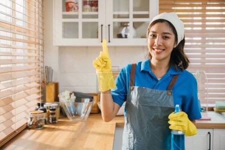 Photo for Young woman in apron and rubber glove ready for house cleaning. Promoting hygiene and housekeeping with spray bottle in hand. Clean disinfect home care. maid with liquid. - Royalty Free Image