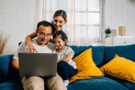 Photo for Family time on the couch as parents and kids engage with a laptop. A young man woman son and daughter search bond and smile in their modern home creating moments of happiness. - Royalty Free Image