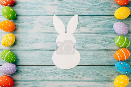 Photo for Easter Day Concept. Top view holiday banner background web design white colorful easter eggs and paper bunny rabbit on blue wood background with copy space, celebration greeting, overhead, template - Royalty Free Image
