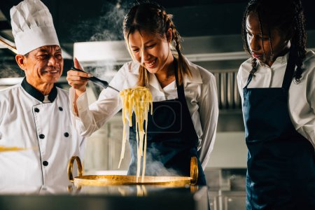 Photo for Chef educates in kitchen. Schoolgirls make Japanese noodle. Kids and teacher at stove. Smiling portrait of learning is modern education. Making dinner with ladle gives joy. Foor Education Concept - Royalty Free Image