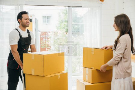 Photo for Homeowners receive professional moving aid indoors. Uniformed movers unload boxes from truck ensuring customer satisfaction during relocation. Efficient service and teamwork shown. Moving Day - Royalty Free Image