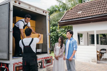 Photo for A couple receives professional assistance in moving to their new house. The teamwork of employees is evident as they unload and lift cardboard boxes during the relocation. Moving Day Concept - Royalty Free Image