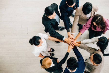 Photo for A top view shows four diverse businesspeople forming a circle stacking their hands. This embodies the concepts of unity teamwork and global collaboration in the corporate world. - Royalty Free Image