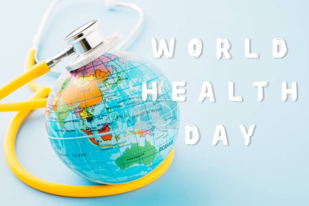 Téléchargez les photos : World Health Day. Top view yellow doctor stethoscope wrapped around world globe isolated on pastel blue background with copy space for text, Save world day, Health care and medical concept - en image libre de droit