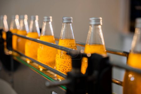 Téléchargez les photos : À l'usine de boissons, une ligne d'embouteillage automatisée remplit les bouteilles transparentes de boissons de graines de basilic ou de chia bio infusées de grenade.. - en image libre de droit