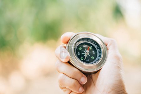 Photo for Hiker searches for direction in the forest holding a compass to overcome confusion. The compass in the hand signifies exploration and finding one way in the wilderness. - Royalty Free Image