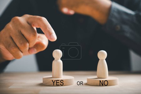Photo for Wooden cube with peg dolls, yes or no choices. Mans hand holding two options depicts decision-making. Red question mark emphasizes the concept. Think With Yes Or No Choice. - Royalty Free Image