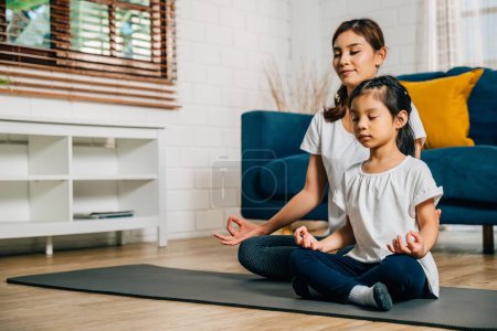Photo for A mother teaches her daughter family yoga focusing on mindfulness and meditation in lotus position. Their smiles showcase happiness togetherness and growth. - Royalty Free Image