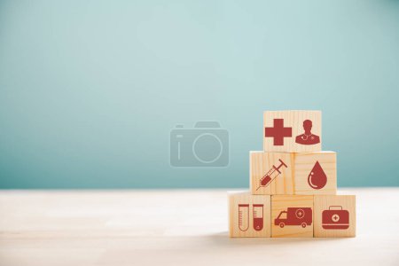 Foto de Los cubos de madera en forma de pirámide simbolizan la atención médica y el seguro. Coronando el icono del seguro médico contra el fondo blanco, proporcionando espacio de copia para las ideas del seguro de salud. - Imagen libre de derechos
