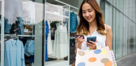 Photo for Fashion accessory overload ,young woman with shopping bags, smartphone, and credit card in front of a store window. Retail therapy for the fashion-savvy - Royalty Free Image