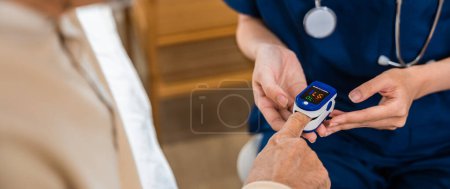Foto de Mujer joven poniendo oxímetro digital de dedo adulto de mediana edad paciente para la medición, enfermera comprobando con dedo pulso oxímetro oxímetro medidor de oxígeno monitor de sangre dedo de anciano mayor en el hospital - Imagen libre de derechos