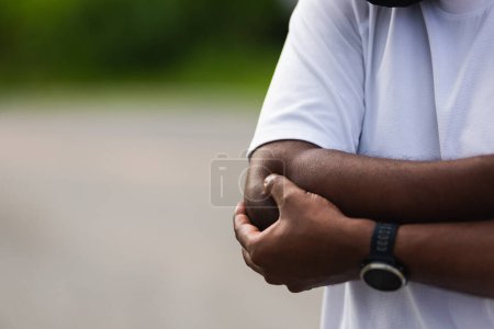 Photo for Close up Asian young sport runner black man wear watch he having elbow pain and use hands joint hold elbow while exercising at the outdoor street health park, healthy exercise Injury from workout - Royalty Free Image