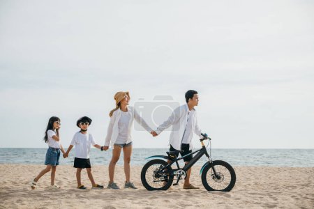 Foto de Parents and children enjoy a beach stroll with bicycles a scene full of happiness smiles and the carefree spirit of a childhood day. Family on beach vacation - Imagen libre de derechos