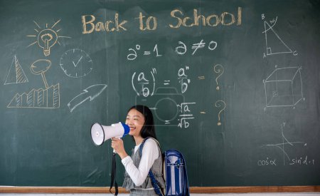 Photo for A girl is standing in front of a chalkboard with the words Back to School written on it. She is holding a megaphone and smiling - Royalty Free Image
