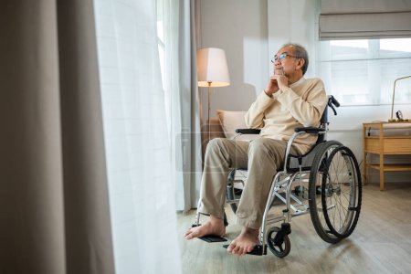 Photo for Lonely older thoughtful sad old man look outside windows in bedroom at retirement home, Asian senior man disabled feel depressed lonely sitting alone in wheelchair looking through window at hospital - Royalty Free Image
