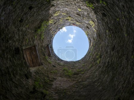 Photo for Stone well hole, old construction from inside, brick walls and blue sky background, fall down in the well concept - Royalty Free Image